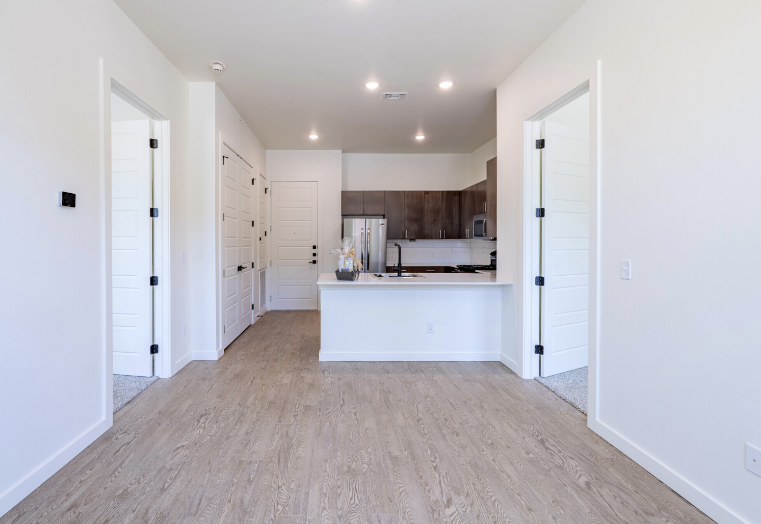 a clean white kitchen with hardwood floors and white cabinets at The Campbell